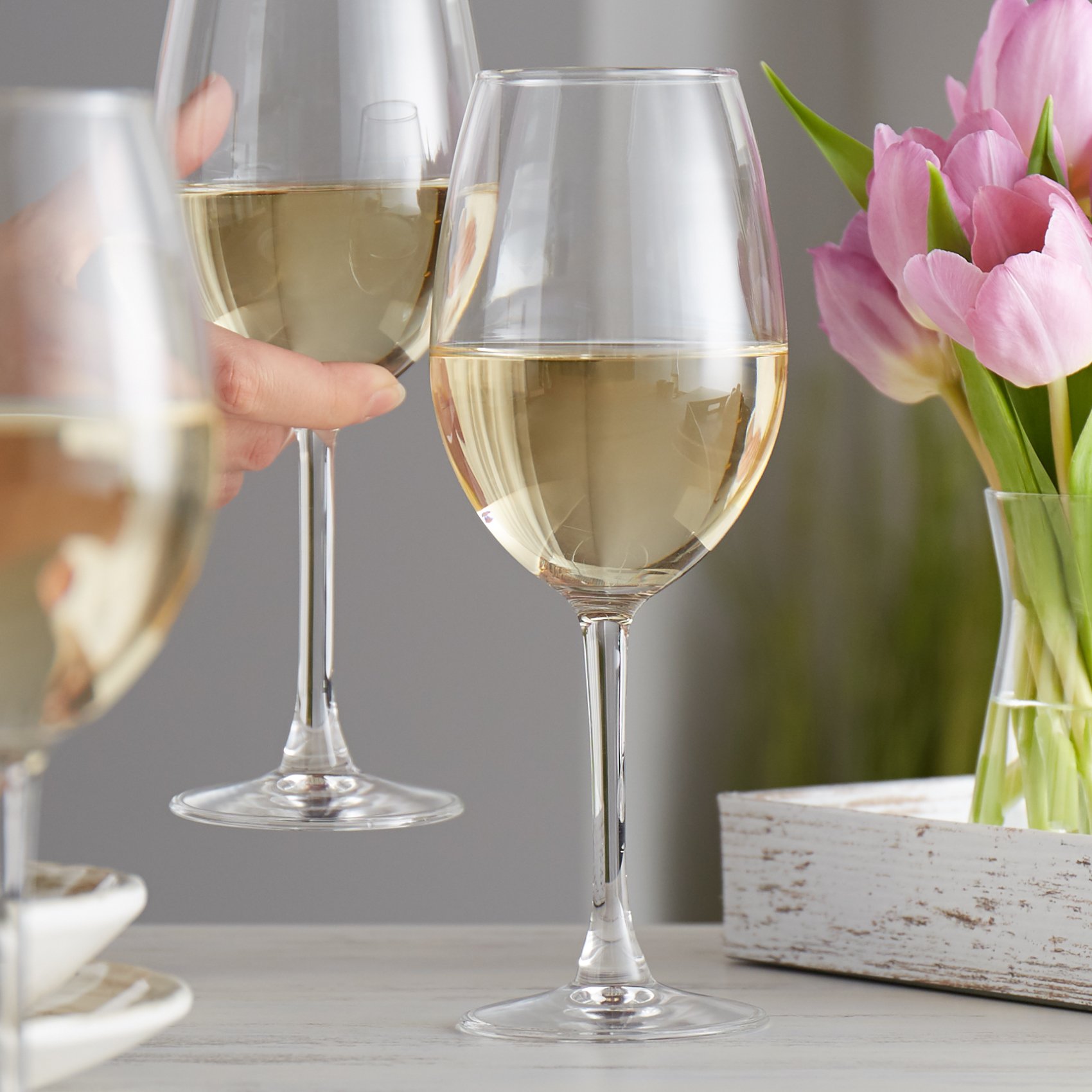 White wine glass filled with sauvignon blanc on an elegant table with tulips in the background