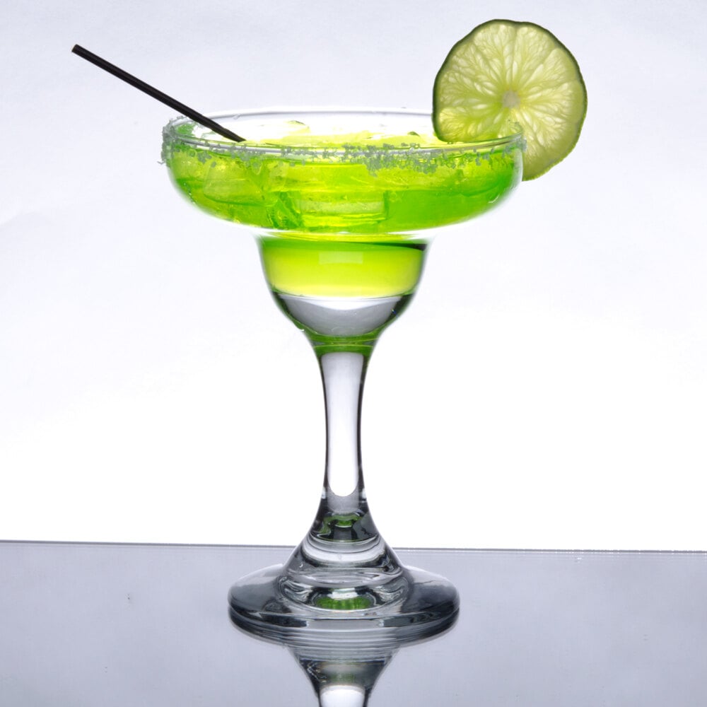a traditional margarita glass filled with green liquid and served with a straw and lime slice