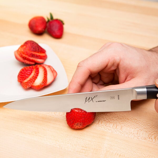 Hand holding Japanese knife and slicing strawberries