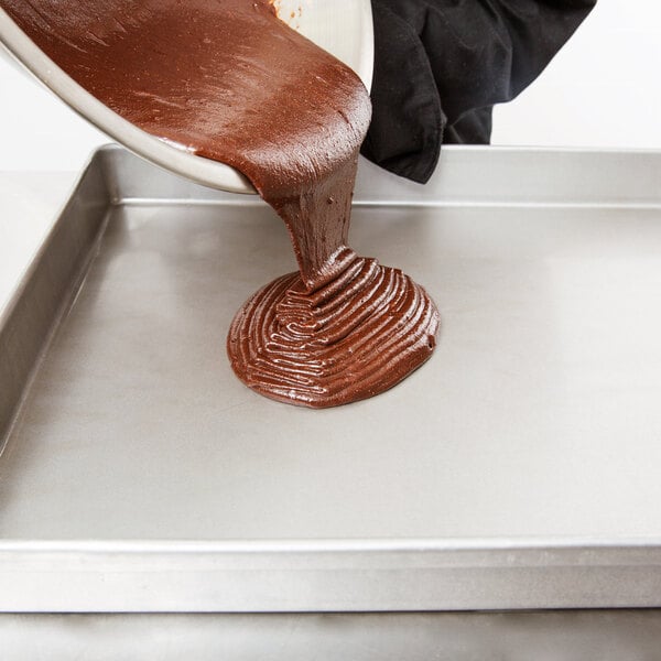 Chocolate cake batter pouring onto a sheet cake pan