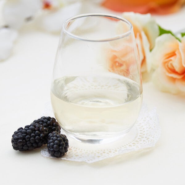 Stemless wine glass filled with white wine on an elegant table with roses in the background