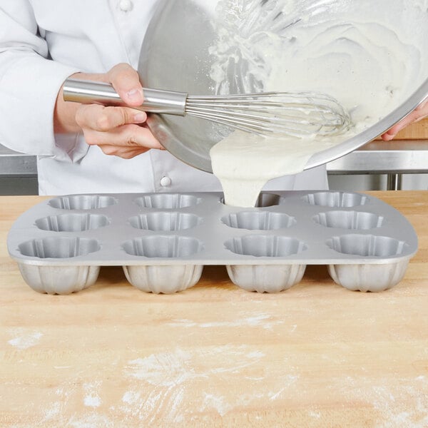 Baker pouring batter into a cupcake pan