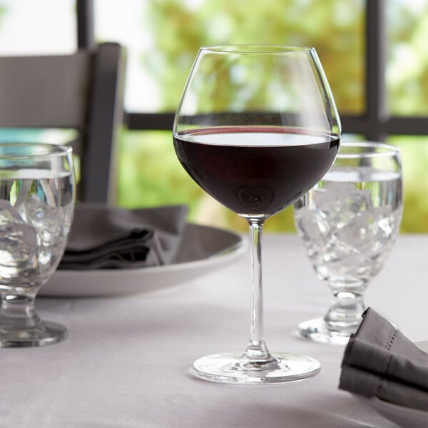 Burgundy wine glass filled with burgundy wine on an elegant table