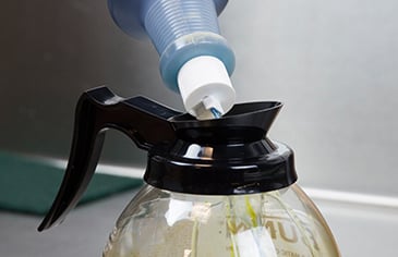cleaning solution being poured around inside circumference of coffee pot