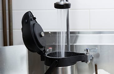 adding hot water from sink to a coffee airpot