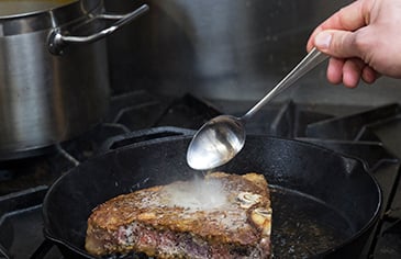 basting a steak with oil