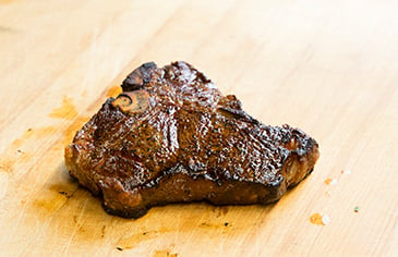 cooked steak on a wooden cutting board
