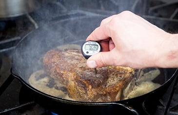 checking the temperature of a steak with a thermometer