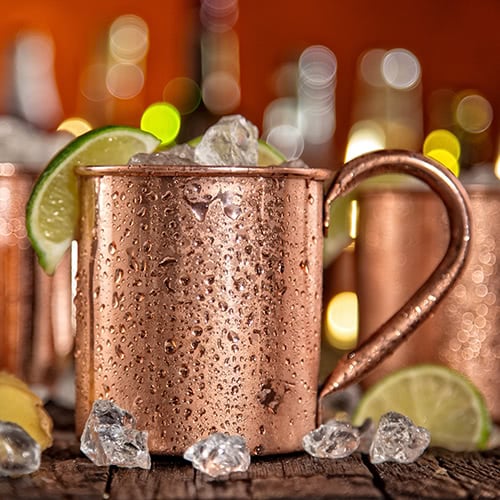 Moscow mule cocktail in a copper mug with ice and limes