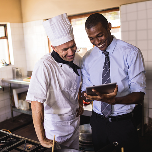 Man holding iPad smiling next to chef