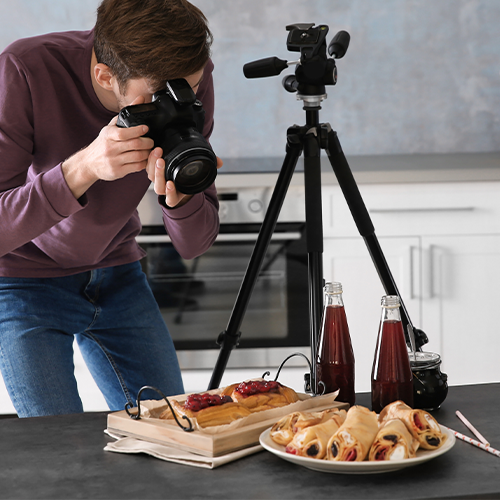 Man holding camera taking a photo of a plate of food