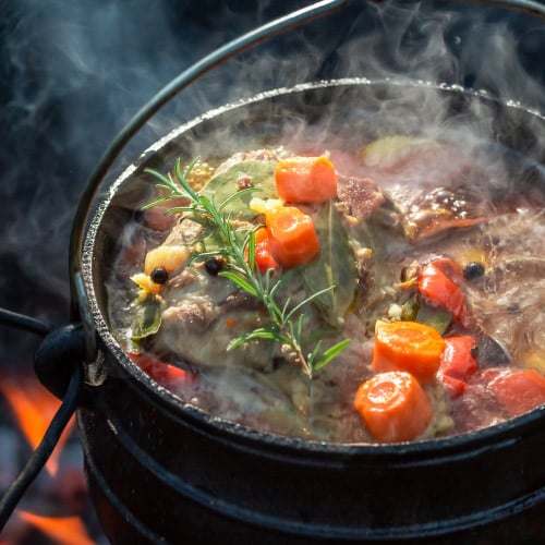 A thick stew of carrots and beef in a hot cast iron pot