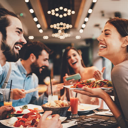 Male and female friends laughing and eating in a restaurant