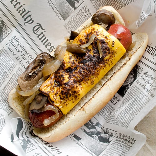 hotdog on grilled bun with melted cheese, onions, and mushrooms
