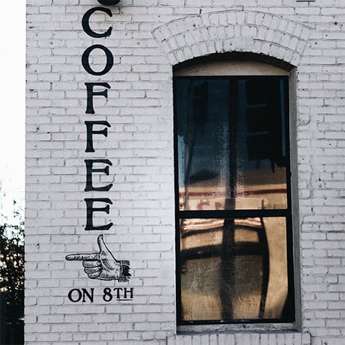 coffee on 8th painted on a brick building with window