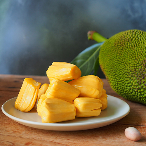 ripe jackfruit on white plate on wooden table