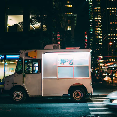 white food truck parked on city street at night near buildings