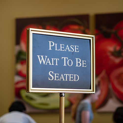 Please wait to be seated sign standing at the front of a restaurant.