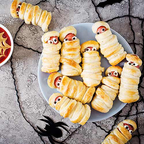 scary sausage mummies in dough with funny eyes on table