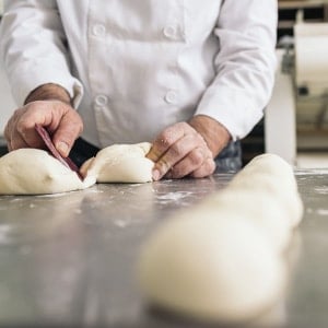baker cutting dough in wholesale bakery