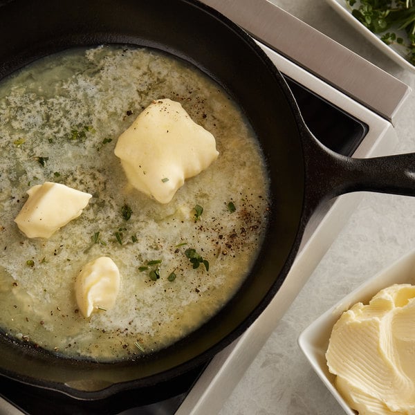 Butter melting in a cast iron skillet with herbs