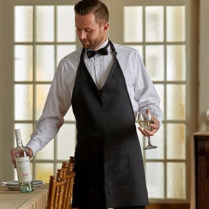 waiter in a bow tie and apron holding a wine bottle and glass