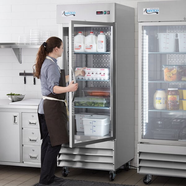 Woman opening up a swing door style reach-in refrigerator