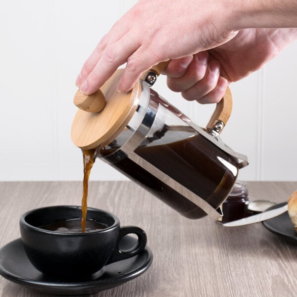Person pouring french press coffee into a mug