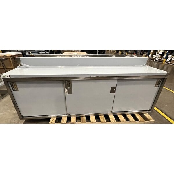 Scratch and Dent Regency 24" x 96" 16 Gauge Type 304 Stainless Steel Enclosed Base Sliding Door Table with Adjustable Midshelf and 6" Backsplash