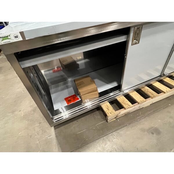Scratch and Dent Regency 24" x 96" 16 Gauge Type 304 Stainless Steel Enclosed Base Sliding Door Table with Adjustable Midshelf and 6" Backsplash