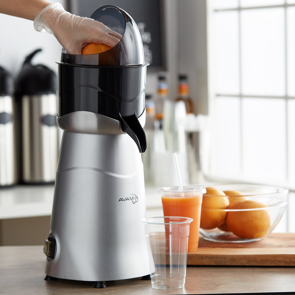 Worker juicing oranges using an electric citrus juicer