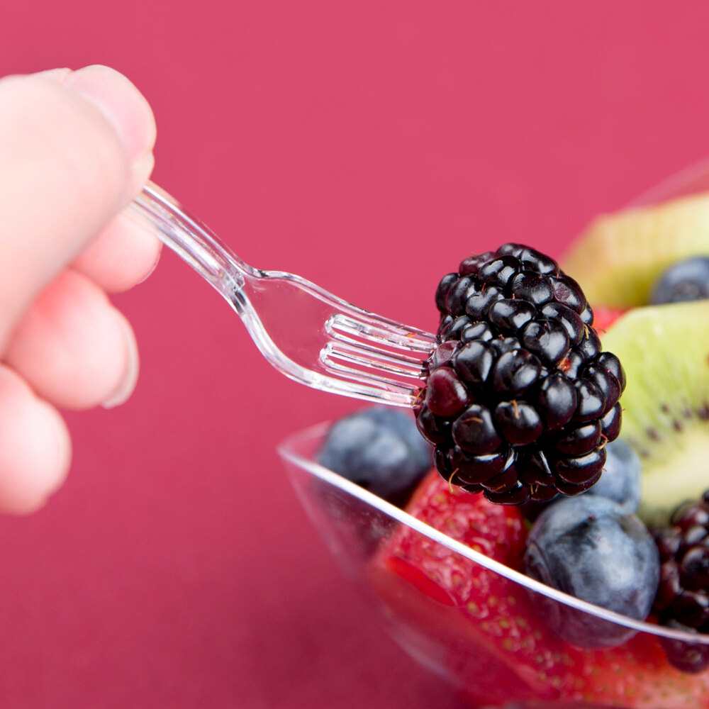 Small, clear plastic fork holding a blackberry