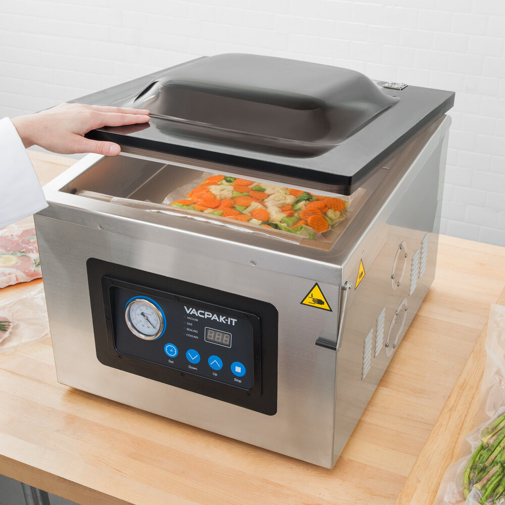Person lifting lid of VacPak-It chamber vacuum sealer to reveal mixed vegetables