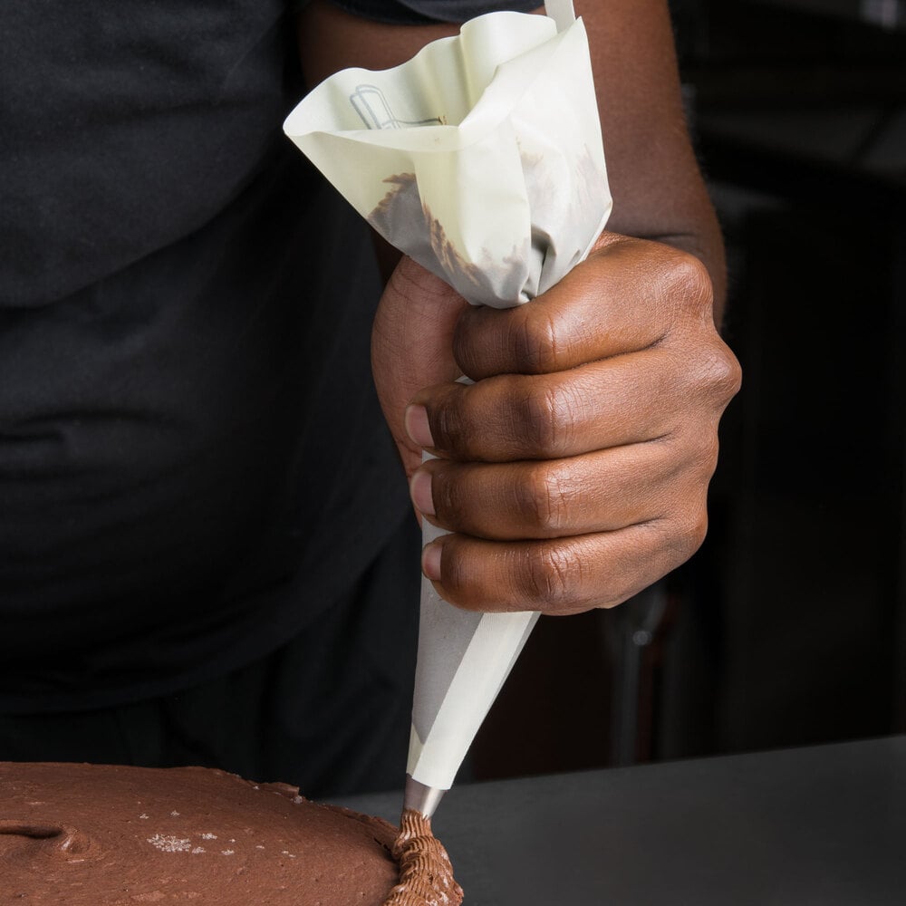 Baker using a nylon pastry bag to decorate a cake