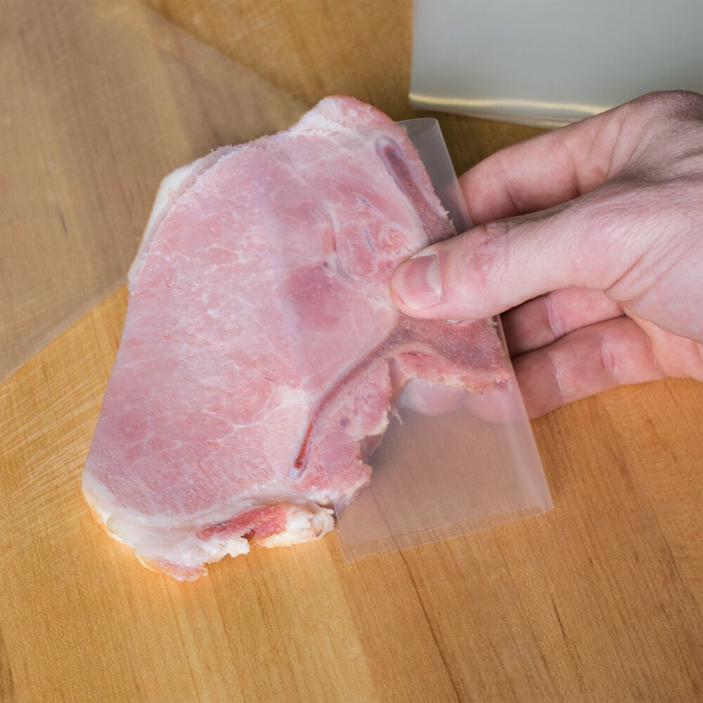 Hand holding bone-in pork chop sealed in bag