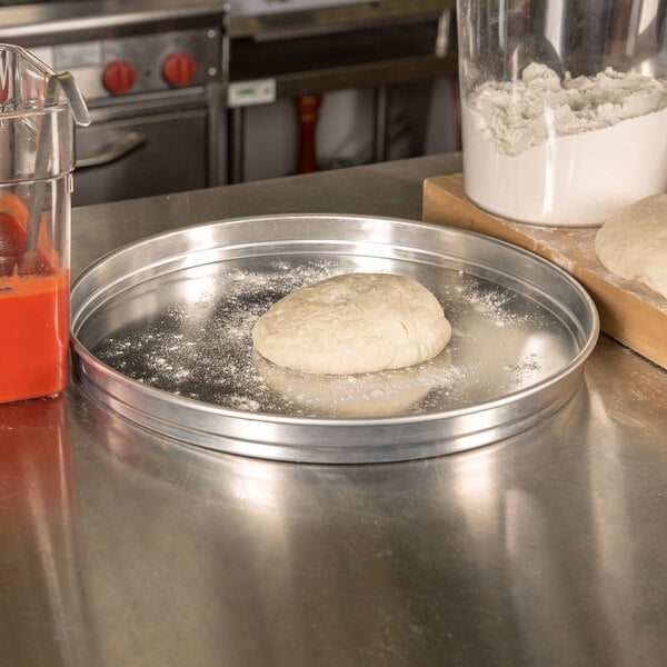 A dough ball on an American Metalcraft aluminum cake pan.