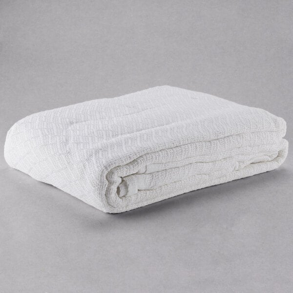 An Oxford white herringbone hotel blanket folded on a gray surface.