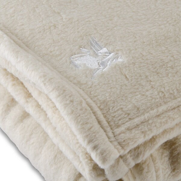 A close up of a white Oxford 100% polyester fleece blanket with white embroidery.