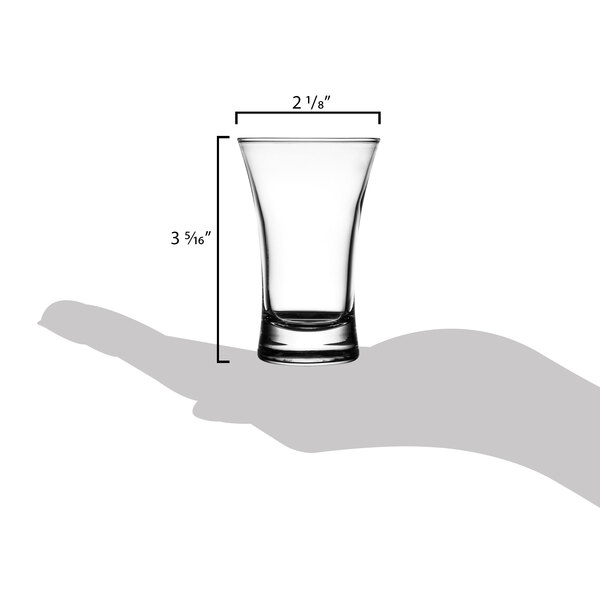 A hand holding an Arcoroc shot glass filled with a drink.