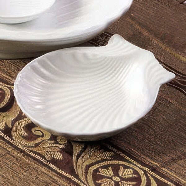 A CAC bright white china shell-shaped bowl on a table.