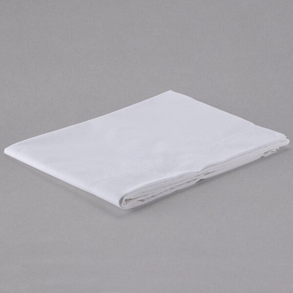 A folded Oxford T200 Superblend white pillow case on a gray surface.