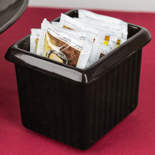 A black Tablecraft rectangle server with packets of tea on a hotel buffet counter.