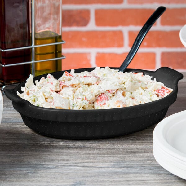 A black Tablecraft casserole dish with green speckles on a table of food.