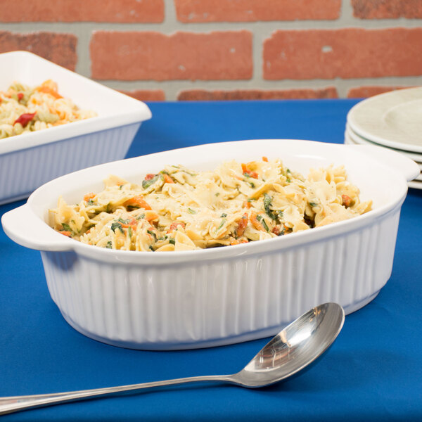 Two white Tablecraft oval casserole dishes with pasta and vegetables.