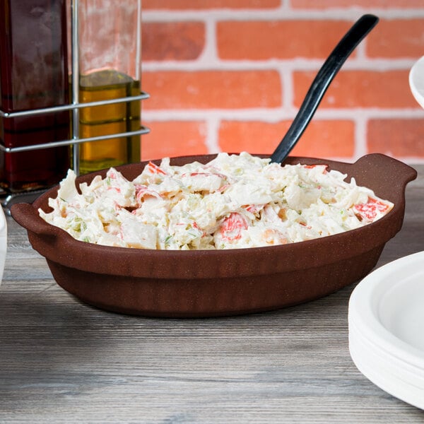 A maroon speckled cast aluminum Tablecraft casserole dish filled with food on a table.