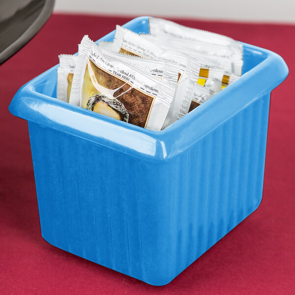 A Tablecraft sky blue cast aluminum rectangle server with tea packets in it on a counter.