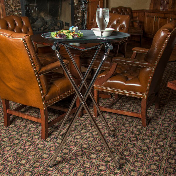 A Carlisle chrome tall tray stand holding a plate of food on a table in a restaurant dining area.