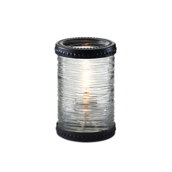 A Sterno clear glass candle holder with bronze accent rings holding a lit candle.