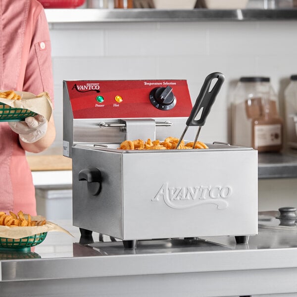 A stainless steel Avantco electric countertop fryer with a basket of curly fries in a commercial kitchen setting.