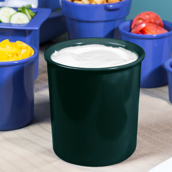 A hunter green cast aluminum bowl with salad dressing in it.